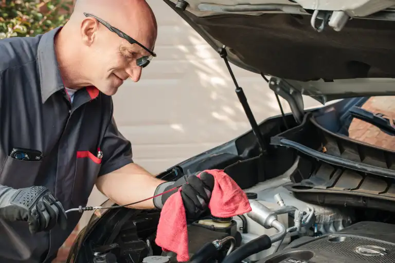 Factory-trained Nissan technician checking engine oil during a mobile service appointment