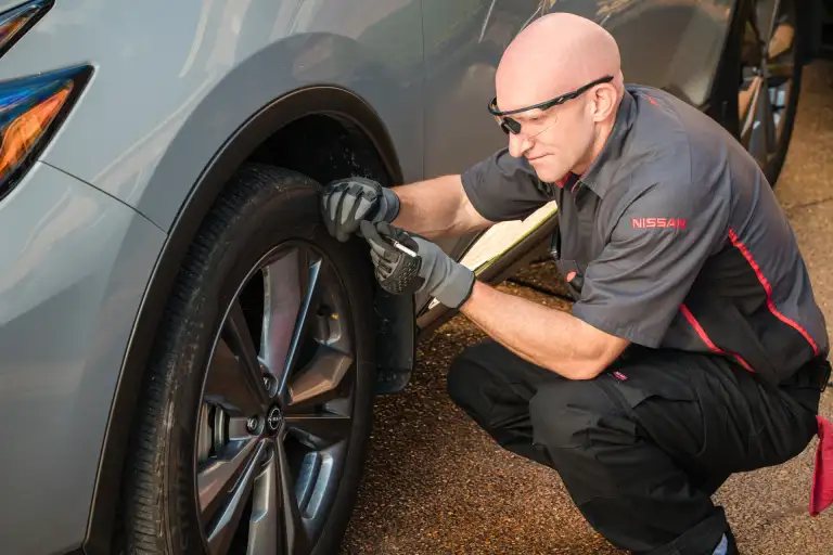 Nissan mobile technician inspecting tire tread during an at-home service visit in Orlando