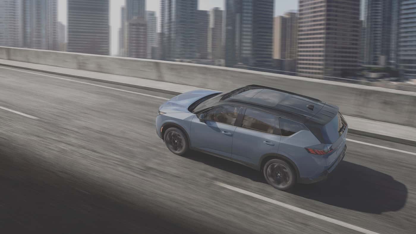 Overhead view of a blue-gray 2027 Nissan Rogue Hybrid with a black roof, showing its side profile and rising beltline