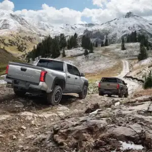 2025 Toyota Tacoma Pair Rear View Driving Towards Snow Covered Mountains