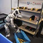 The History Making Atlas, The AI Robot, Picking Up A Plastic Box In A Workshop