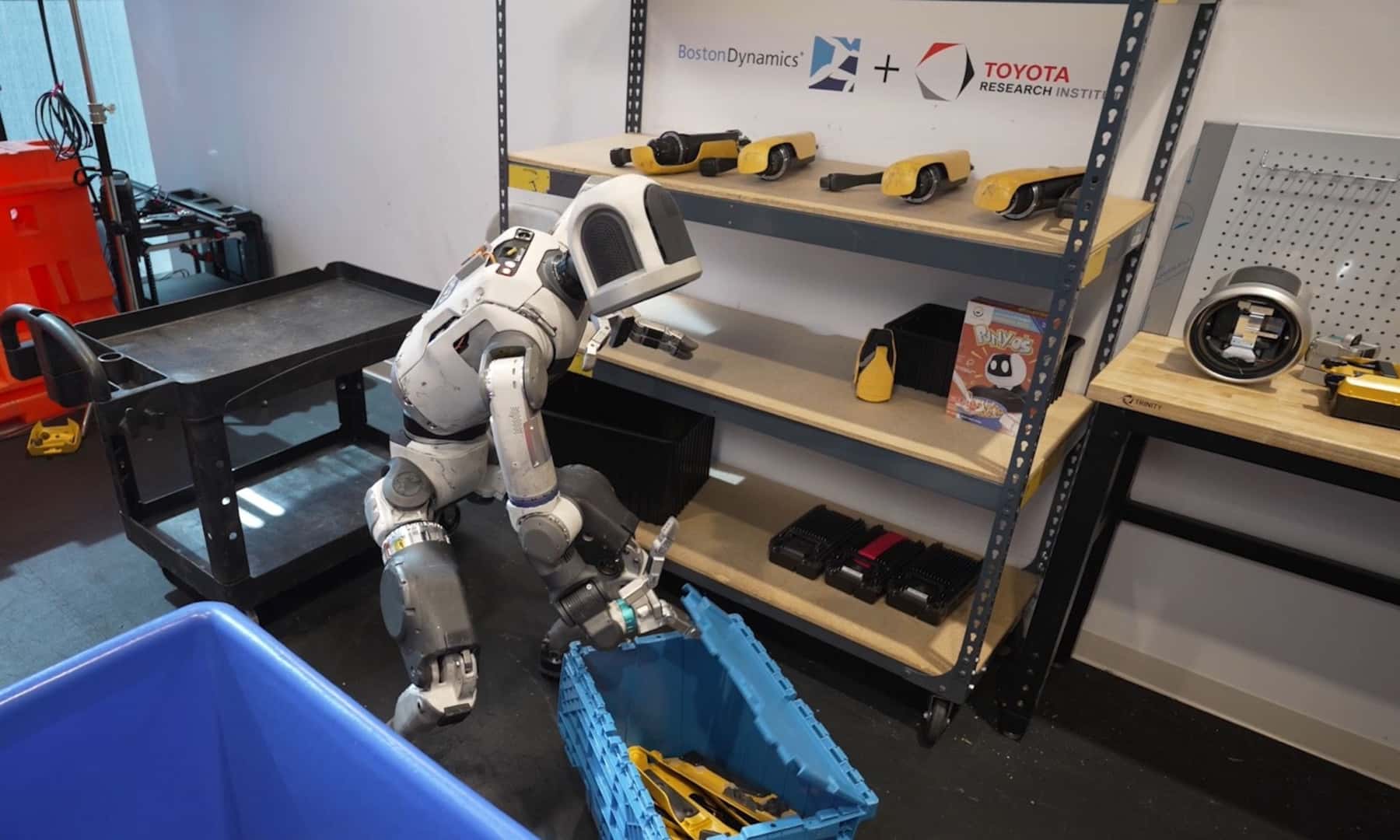 The History Making Atlas, The AI Robot, Picking Up A Plastic Box In A Workshop