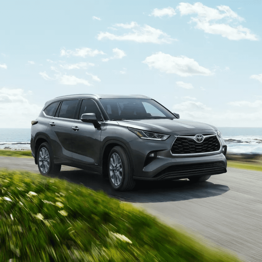 2026 Toyota Highlander Hybrid gliding beside the ocean, showcasing its sleek design and hybrid efficiency