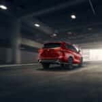 a red toyota highlander driving under a bridge