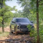 sequoia trailhunter partially obscured by trees on a bumpy road path