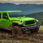 A lime Jeep Gladiator driving over mud on a hill