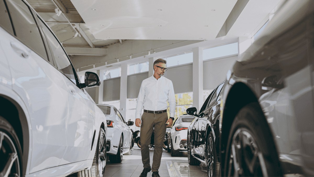 A man walking through a row of cars inside a dealership
