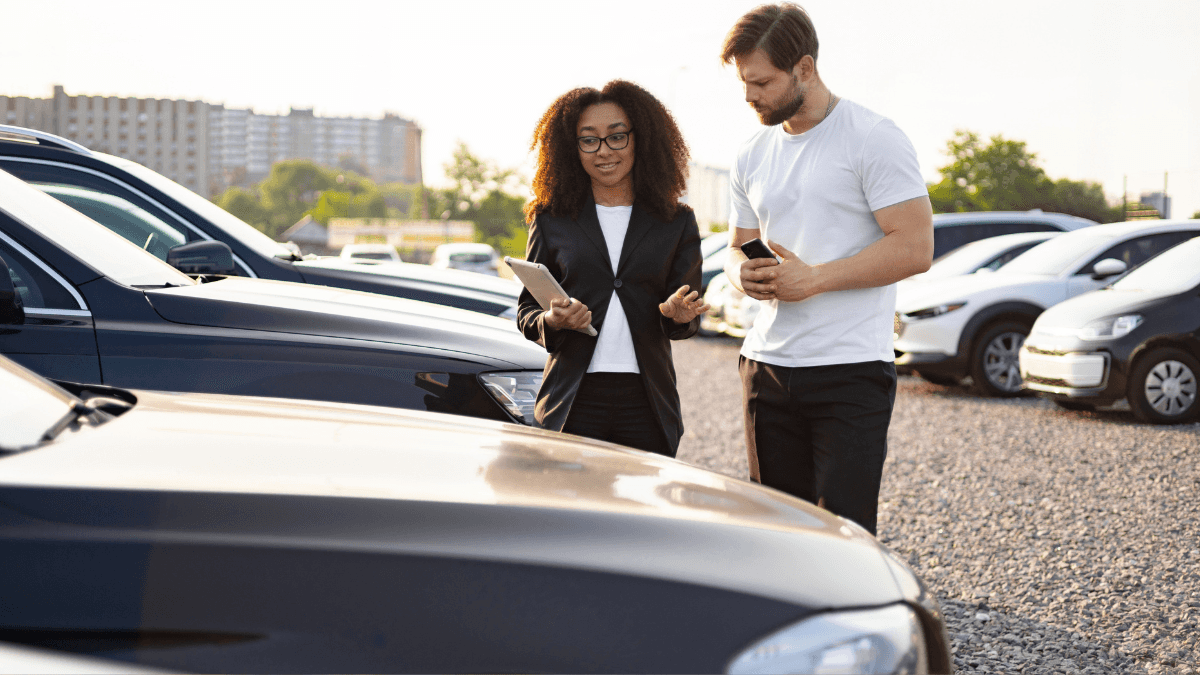 A car salesperson showing a customer the options on their dealership lot
