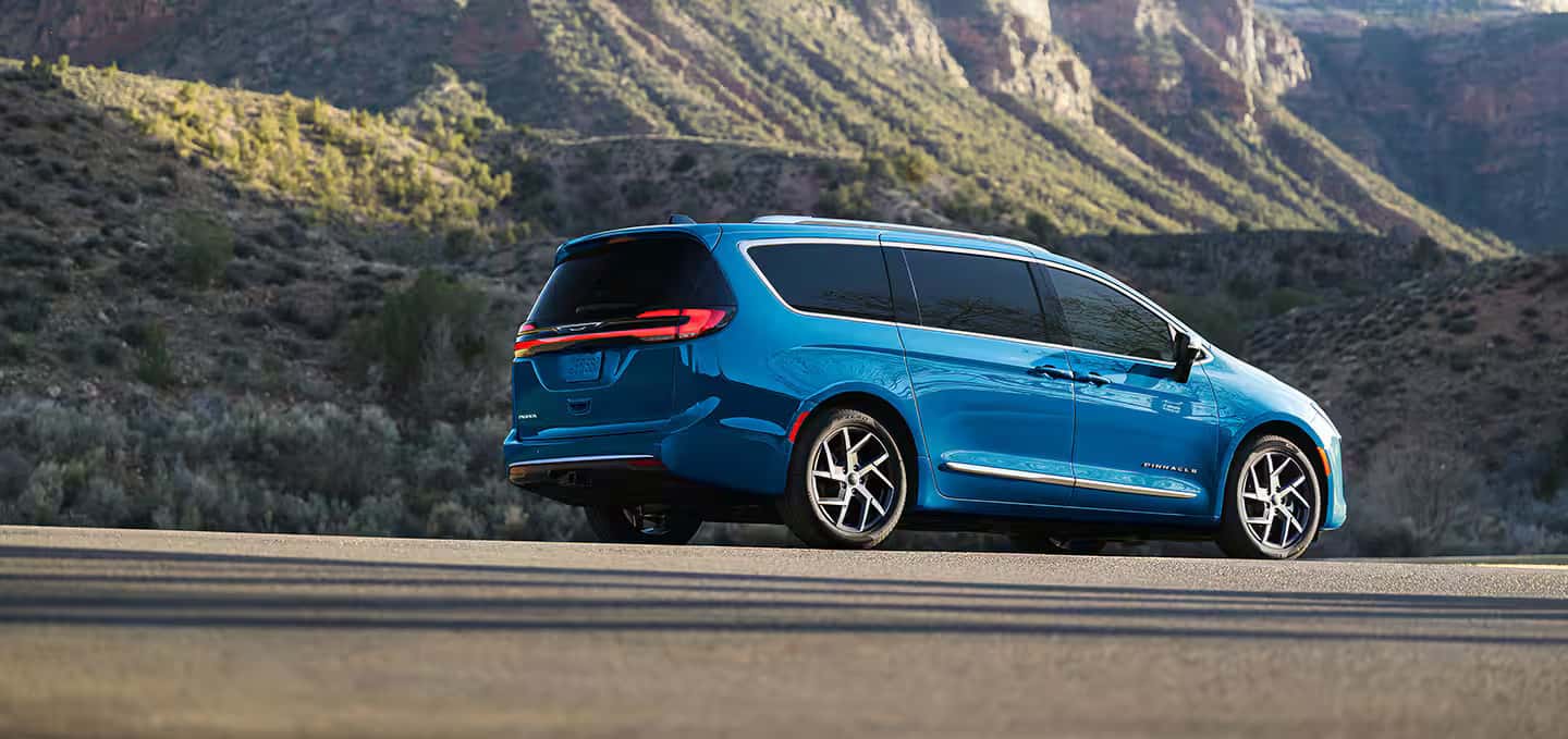 A blue Chrysler Pacifica parked outside near a mountain range