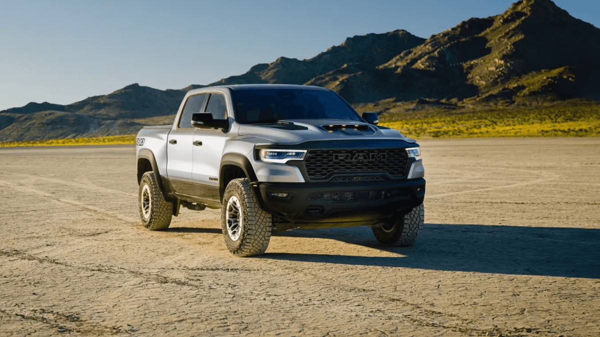 A blue-gray RAM 1500 parked on an empty plain near a mountain range