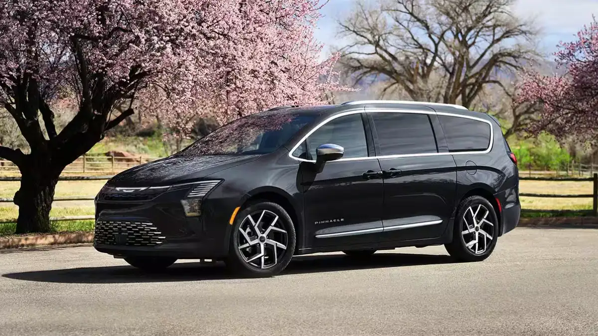 A black Chrysler Pacifica parked near a field with cherry blossom trees