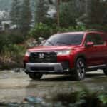 A red Honda Pilot driving through rain off-road