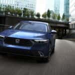A front view of a blue Honda Accord driving through a city