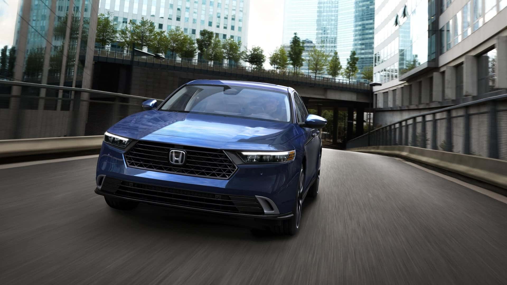 A front view of a blue Honda Accord driving through a city