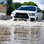 A white car driving through a flooded street