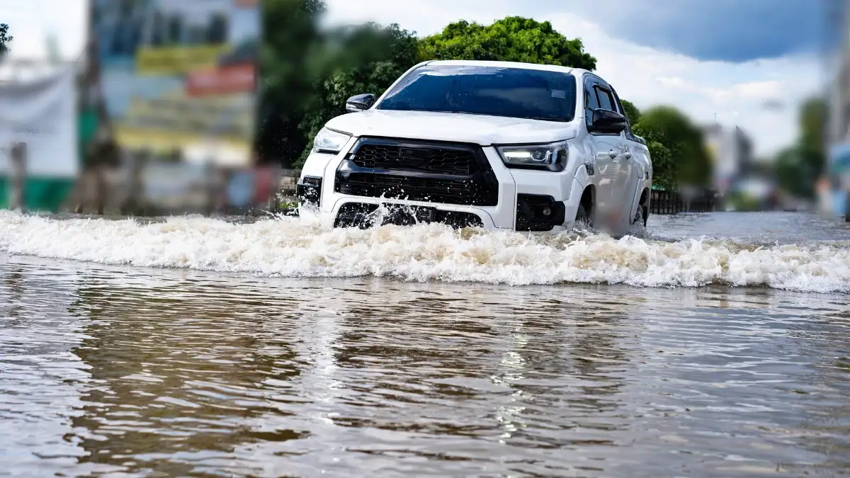 A white car driving through a flooded street