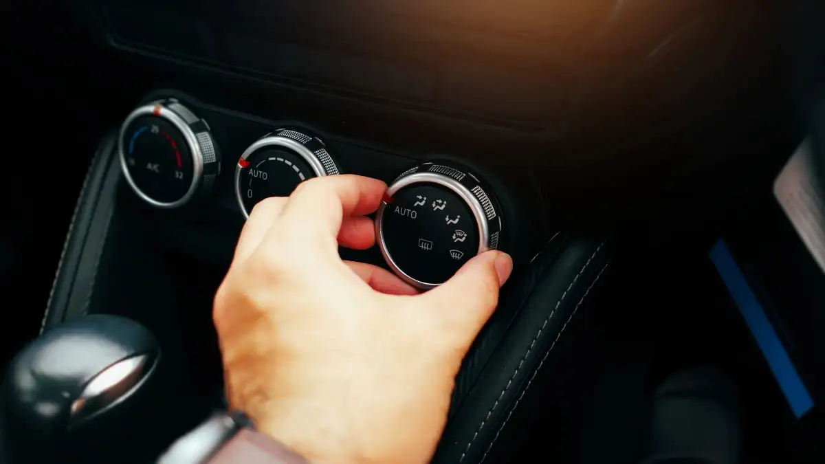 A driver adjusting their vehicle's air conditioning settings