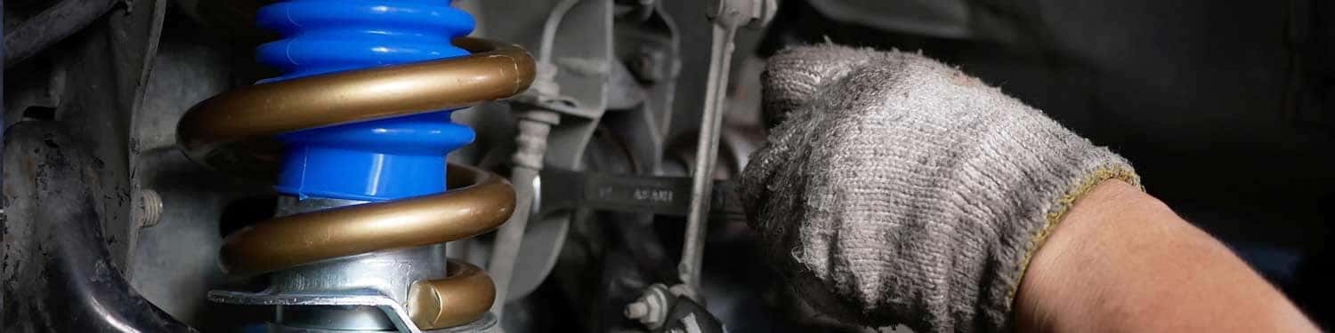 Close up view of a service tech inspecting a vehicle's suspension