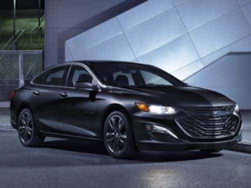 2024 Chevy Malibu Midnight Edition parked outside a modern building at night