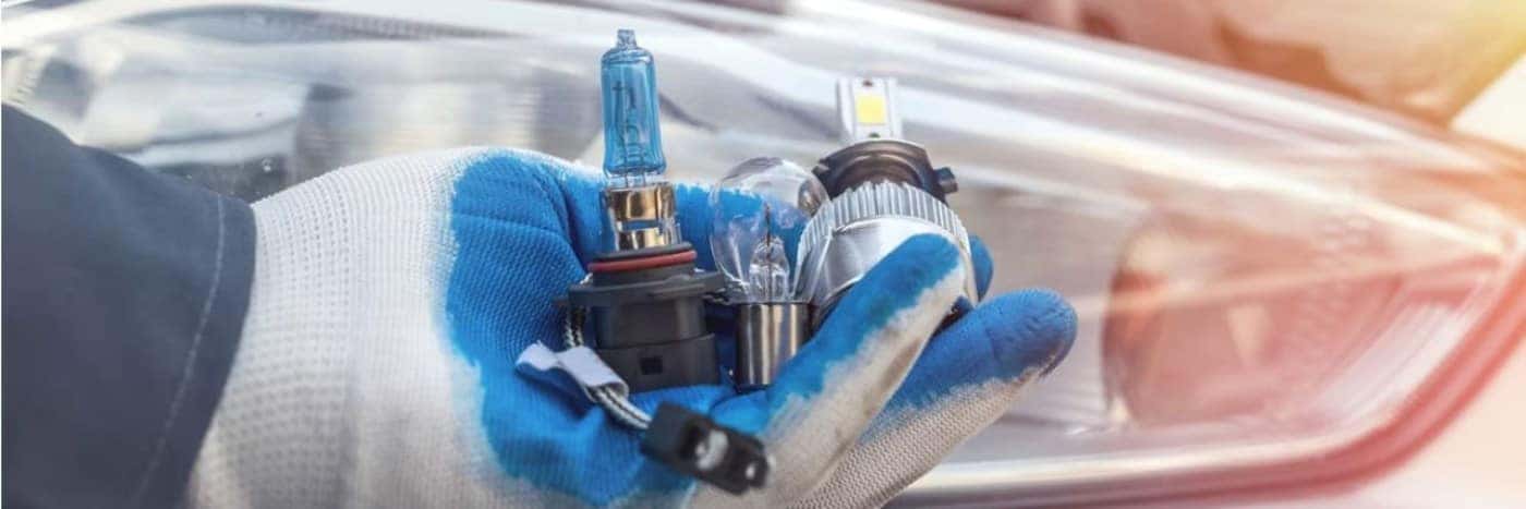 Close up view of someone wearing gloves and holding headlight bulbs