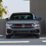 Front view of a grey 2026 Volkswagen Jetta GLI parked in a modern concrete structure.