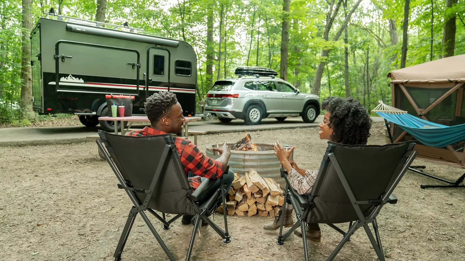 campers sitting by a Volkswagen vehicle hitched up to a camper