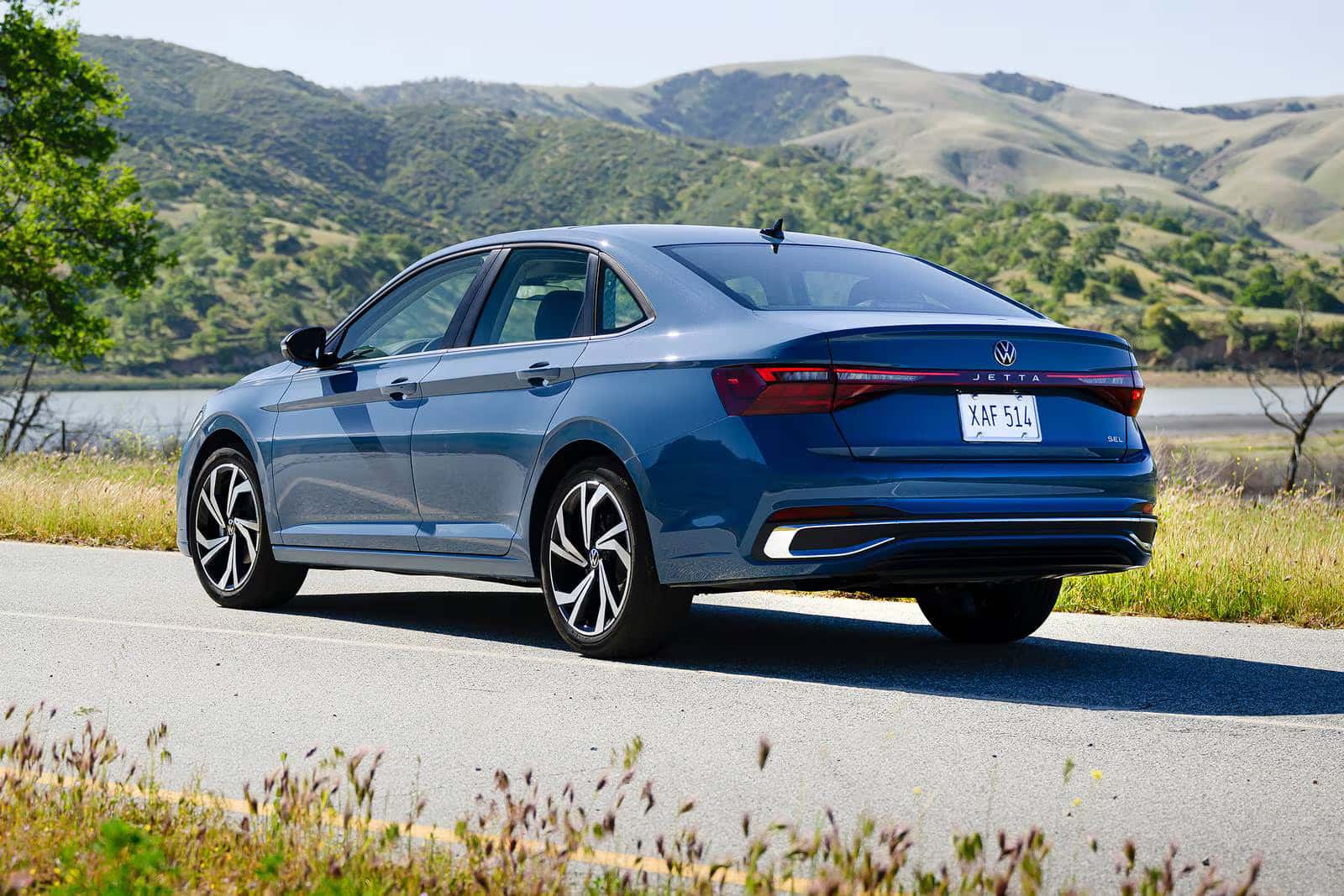 a 2026 Volkswagen Jetta parked on a road with a view of a body of water and a mountain range in the back ground