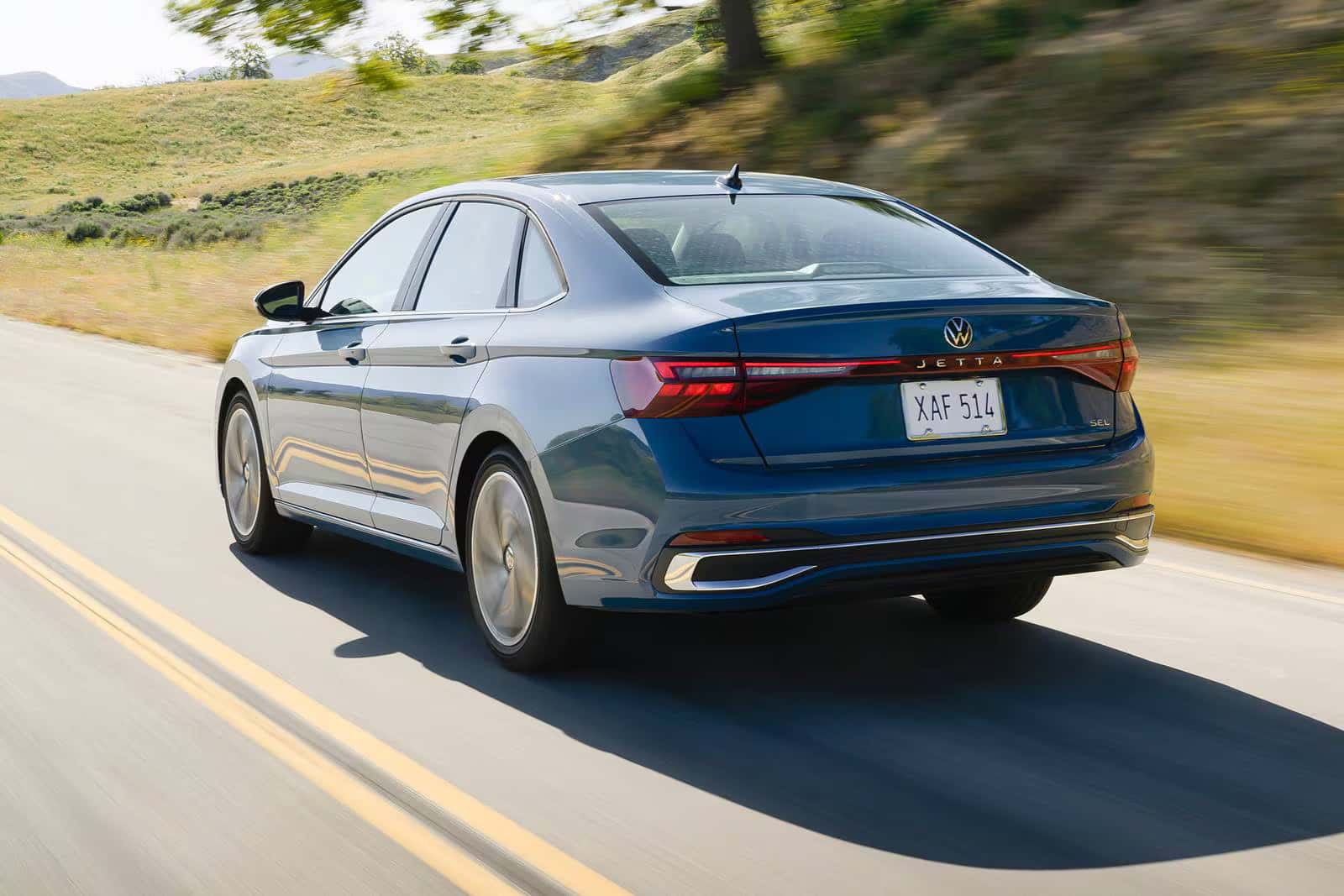 The 2026 Volkswagen Jetta driving on a road next to an open field