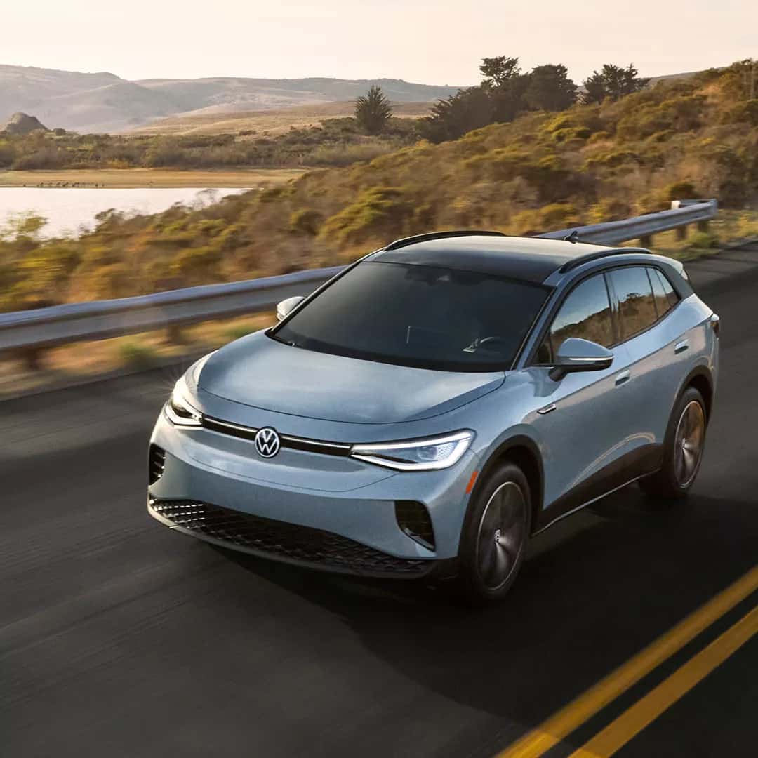 The new 2026 Volkswagen ID.4 driving on a road with a nature view in the background