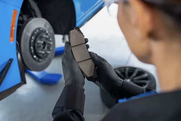 Cadillac-certified technician inspecting new brake pads during a professional brake service and brake repair appointment.