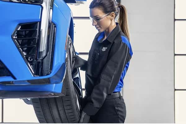 Cadillac-certified technician performing a tire rotation service on a Cadillac vehicle during routine maintenance.
