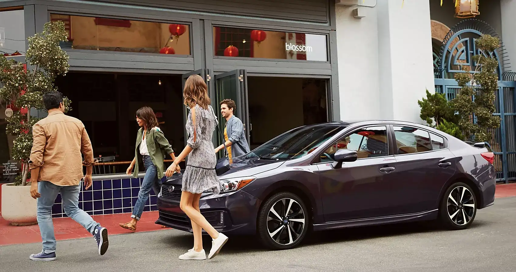 Recent college graduate standing next to a new Subaru vehicle