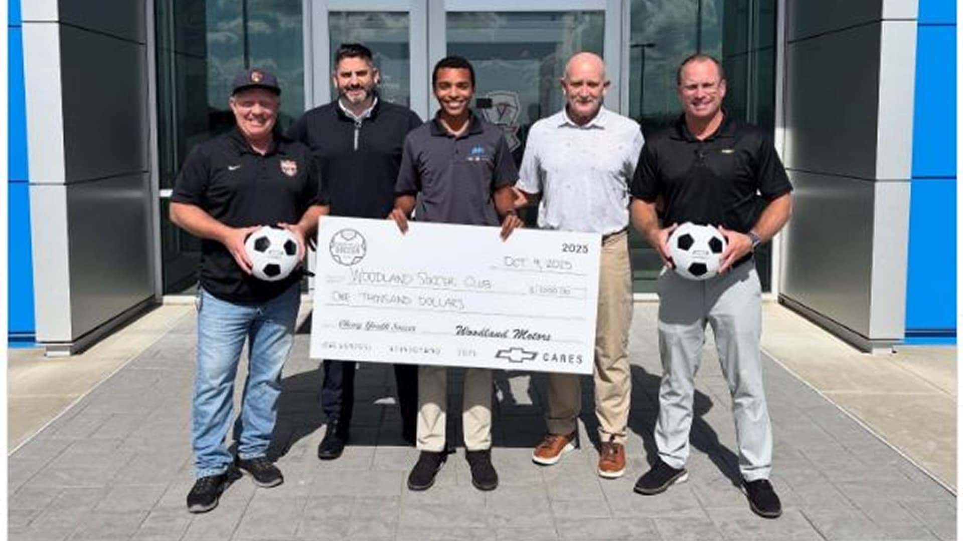 woodland soccer club holding large check