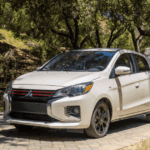 2024 Mitsubishi Mirage front three quarter exterior in white parked on stone driveway showing grille, headlights, and alloy wheels