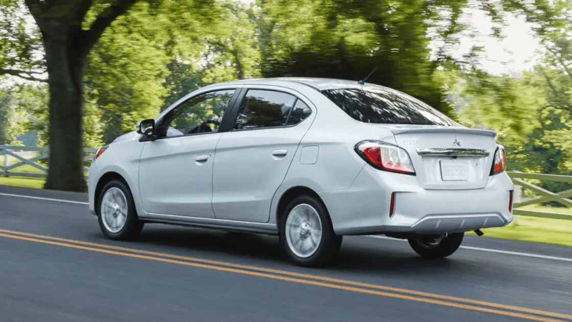 2024 Mitsubishi Mirage G4 rear three quarter exterior driving on tree lined road highlighting sedan body lines and taillights