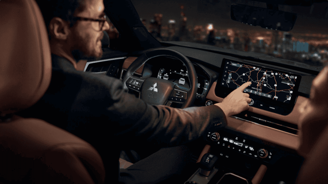 Interior view of a 2024 Mitsubishi Outlander, showcasing the modern dashboard with a man interacting with the touchscreen display.
