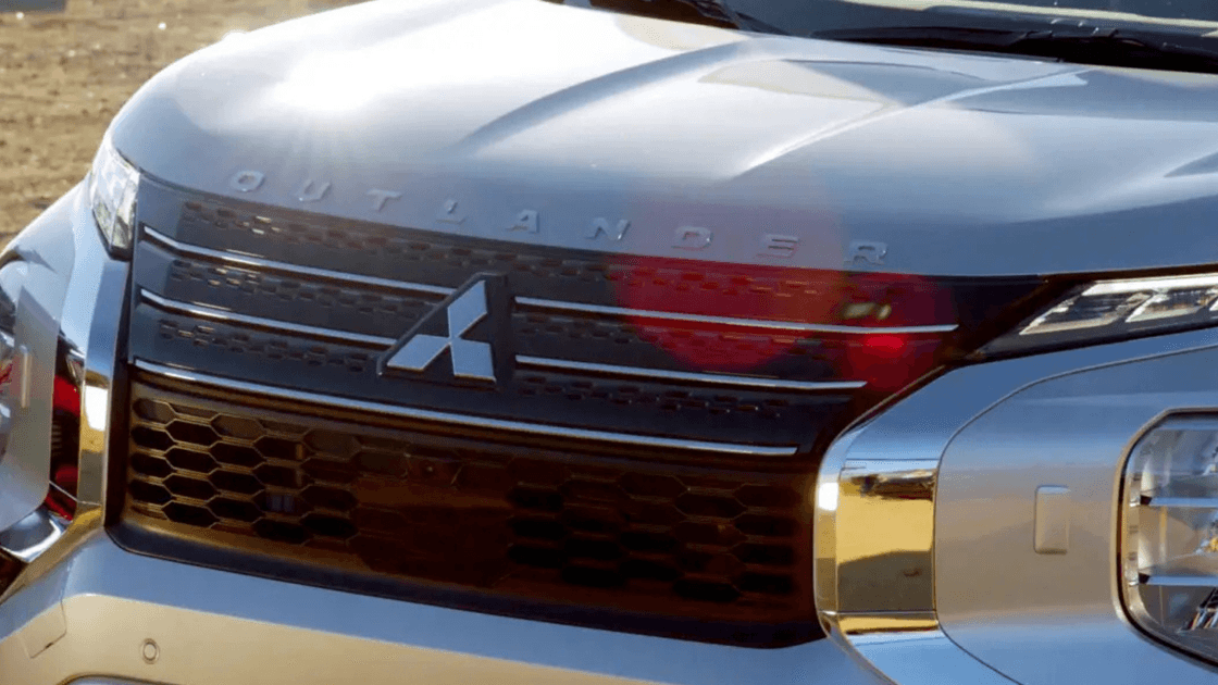 2024 Mitsubishi Outlander front grille close up showing Mitsubishi emblem, bold grille design, and LED headlight detailing