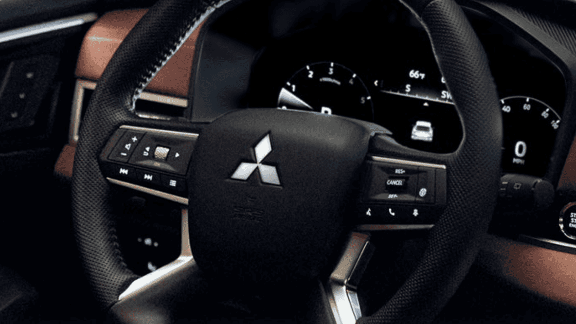 Close-up of the 2024 Mitsubishi Outlander's steering wheel, featuring the Mitsubishi logo and control buttons.
