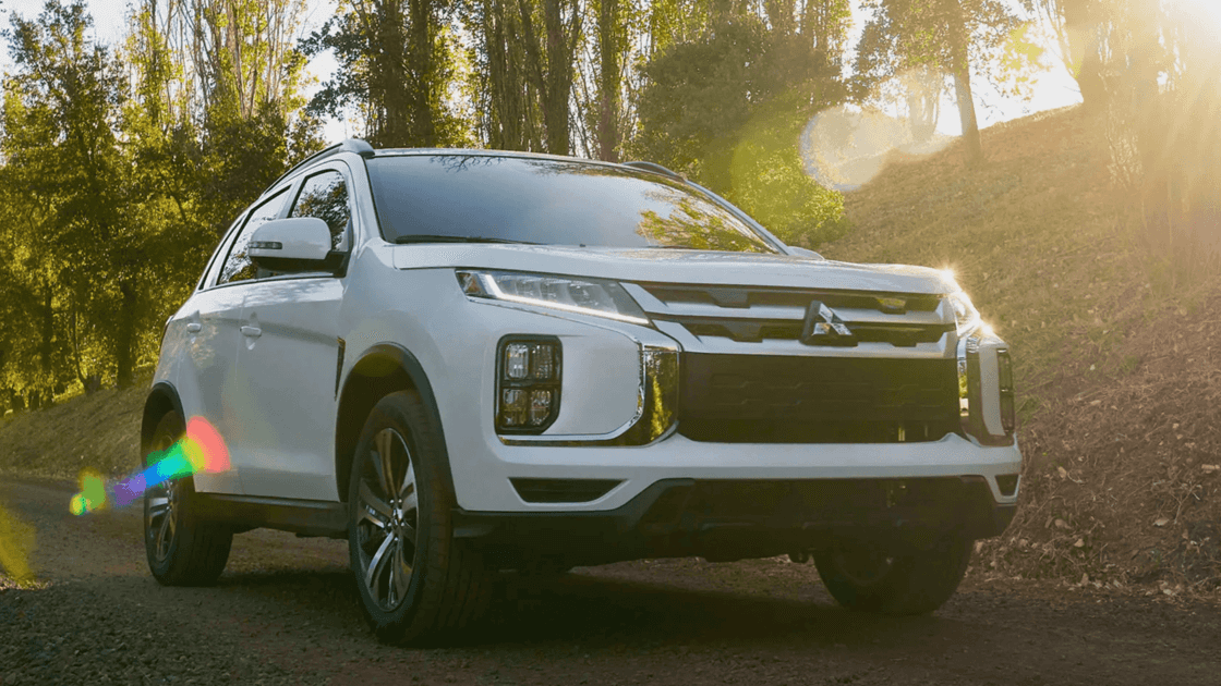 2024 Mitsubishi Outlander Sport front three quarter exterior in white on dirt trail highlighting LED headlights, grille, and SUV stance
