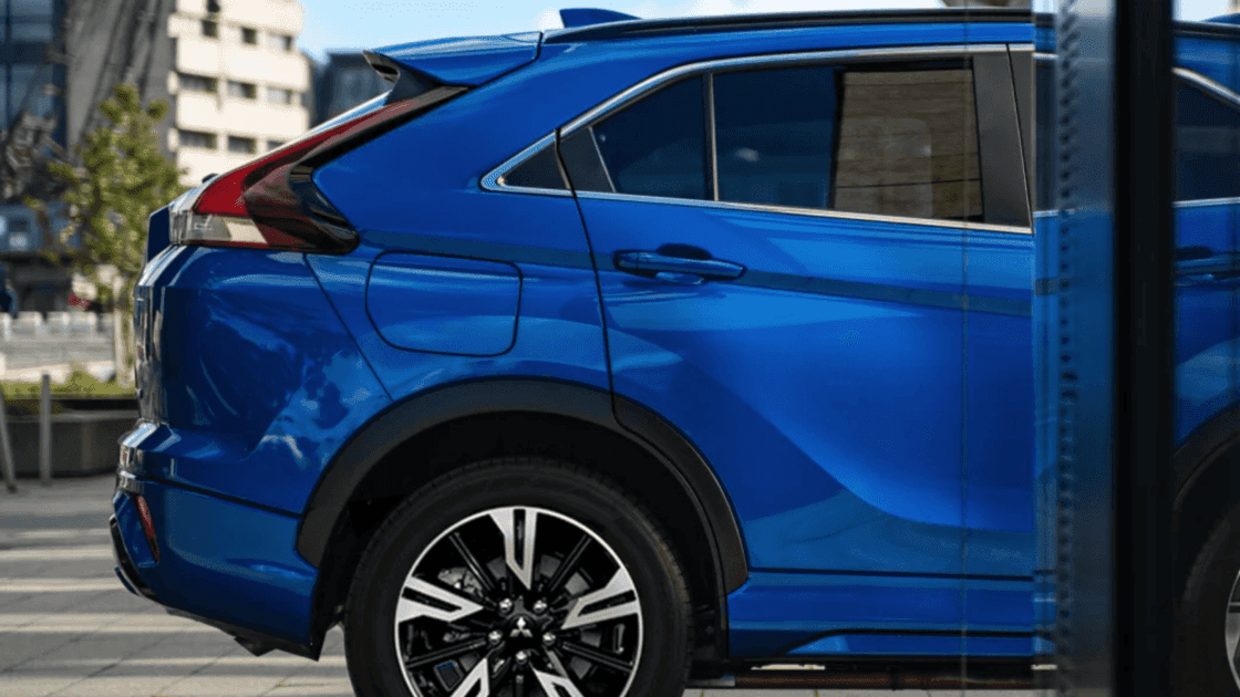2025 Mitsubishi Eclipse Cross rear side exterior in blue highlighting sculpted body lines, alloy wheels, and rear quarter design