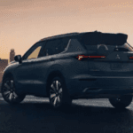 2026 Mitsubishi Outlander rear three-quarter view at dusk with city skyline in blue