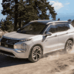 2025 Mitsubishi Outlander PHEV front three quarter exterior driving on dirt trail highlighting plug in hybrid SUV design
