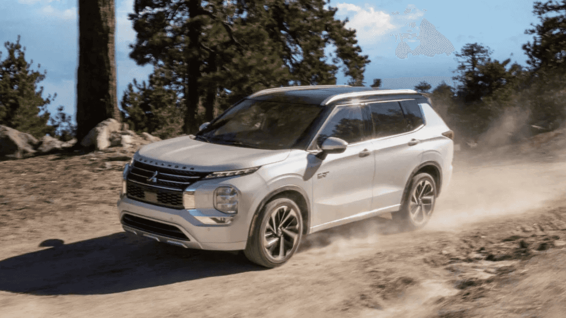 A silver 2025 Mitsubishi Outlander driving on a dirt road surrounded by trees and rocky terrain.