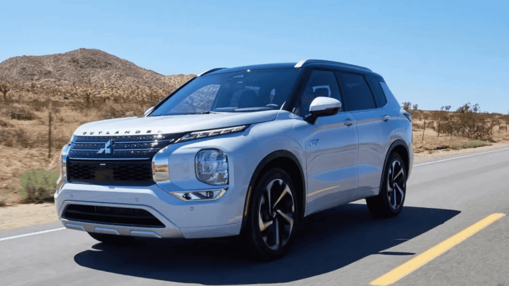 2025 Mitsubishi Outlander PHEV silver SUV driving on desert highway in daylight
