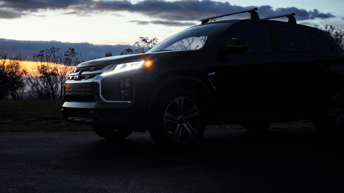 2025 Mitsubishi Outlander exterior at dusk showing LED headlights, roof rails, and SUV silhouette