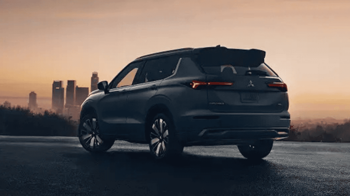 2026 Mitsubishi Outlander rear three-quarter view at dusk with city skyline in blue