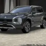 2026 Mitsubishi Outlander front three quarter exterior in dark gray showing LED lighting, bold grille, and midsize SUV profile