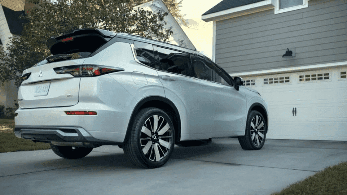 2026 Mitsubishi Outlander white SUV parked in driveway with rear styling and black roof trim