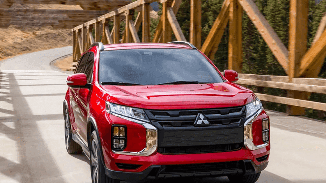 2026 Mitsubishi Outlander Sport red SUV driving across wooden bridge with black grille