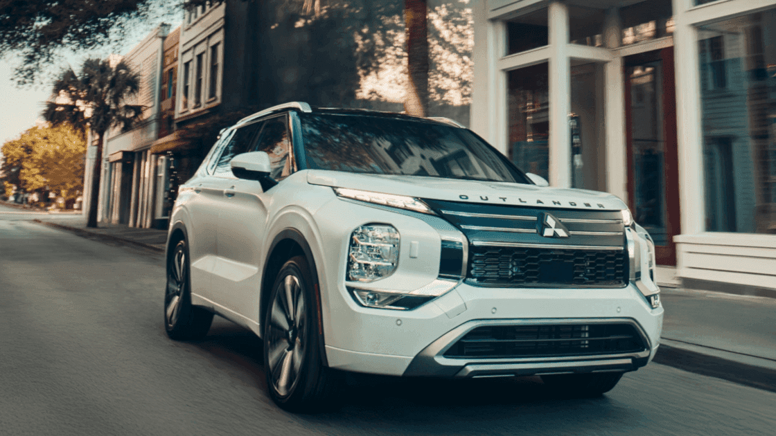 2026 Mitsubishi Outlander white SUV driving through city street with bold front grille